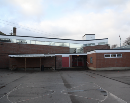 Existing exterior image of red brick school sports hall with inverted pitched flat roof