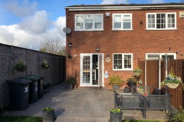 The rear elevation of a two storey house with patio